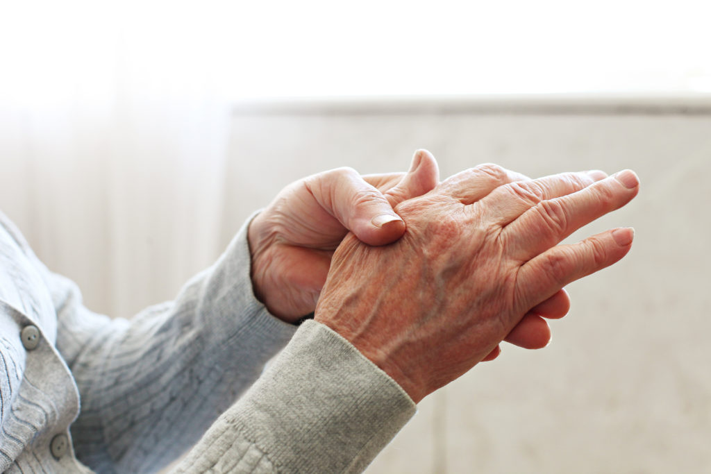 Elderly woman applying moisturizing lotion cream on hand palm, easing aches. Senior old lady